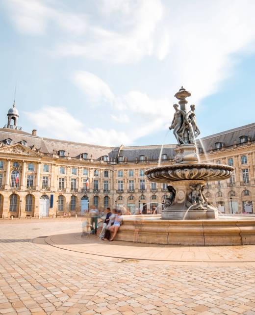 View on the famous La Bourse square with fountain in Bordeaux city, France. Long exposure image technic with motion blurred people and clouds